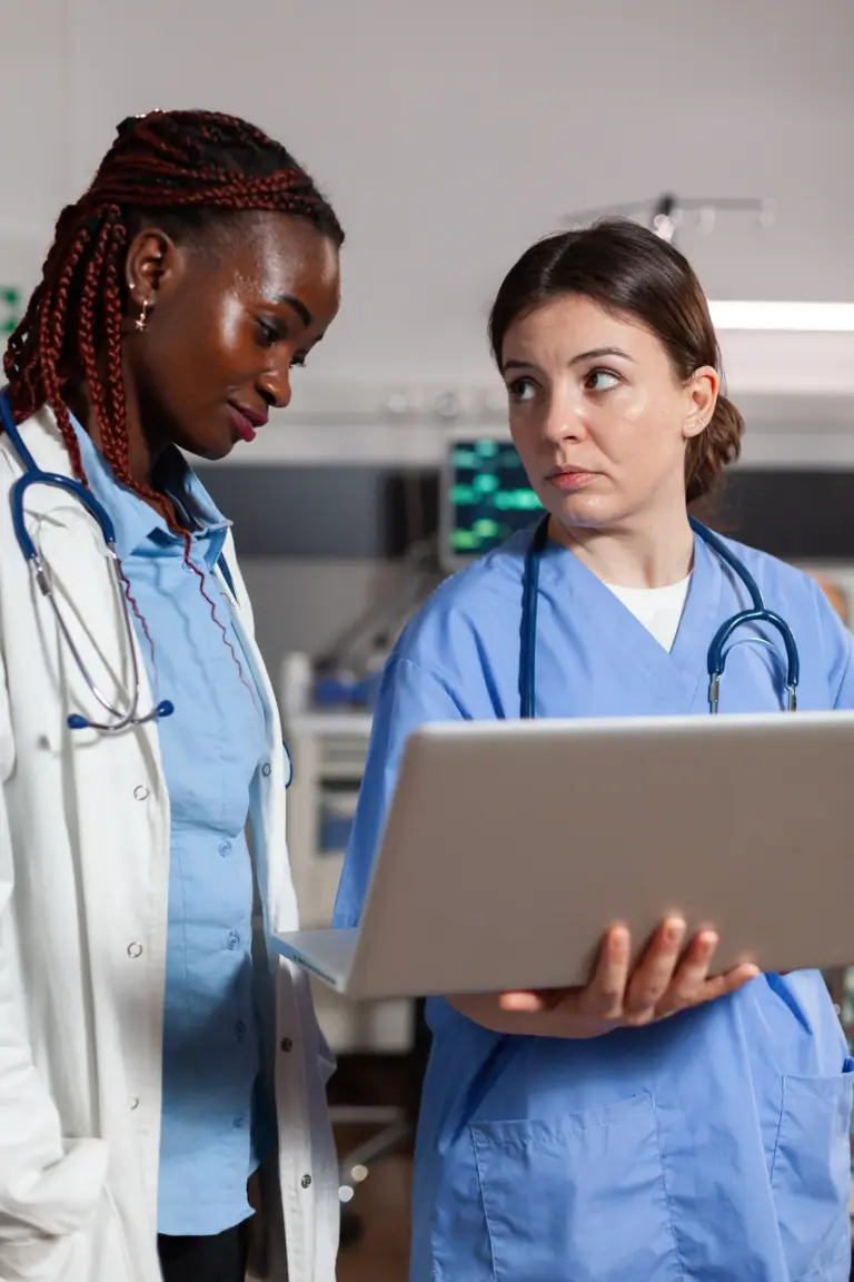 Two clinicians discussing information on a laptop.