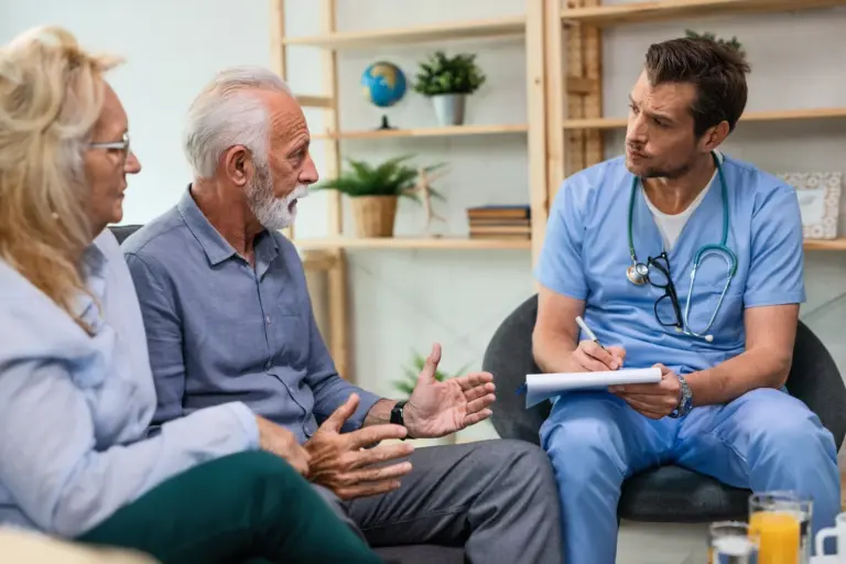 A clinician listening to an older couple and taking notes.