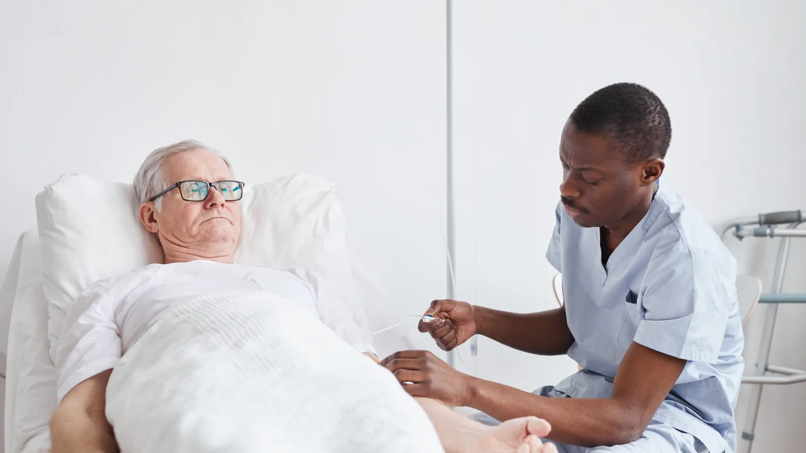 A nurse placing a pulse oximeter on an older man's finger at the bedside.